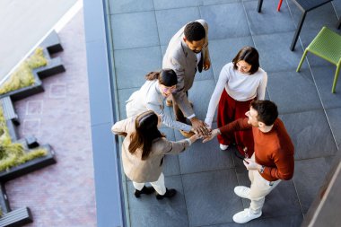 Beş bireyden oluşan canlı bir toplantı, yoldaşlık ve takım çalışmasını kutluyor, açık gökyüzü altında, yeşilliklerle dolu modern bir açık alanda birbirlerinin arkadaşlığının tadını çıkarıyorlar..