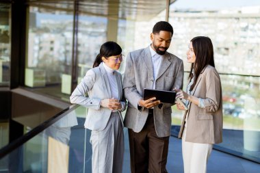 Üç meslektaş parlak bir ofiste bir tableti birlikte incelerken bir tartışmaya giriştiler. Atmosfer yaratıcılık ve işbirliği ile dolu..