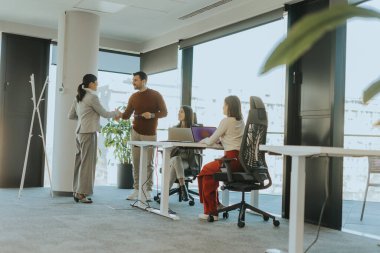 Dört iş adamından oluşan bir grup, doğal ışıkla dolu çağdaş bir ofiste dinamik bir toplantı yapıyor. Fikirler değiş tokuş edildikçe sohbetler başlar.