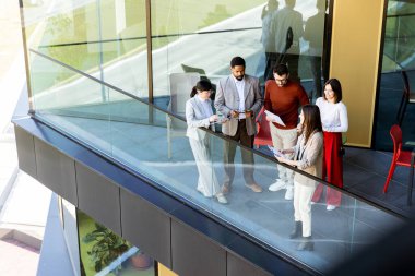 Dört profesyonel balkonda toplanıp parlak güneş ışığının tadını çıkarırken proje planlarını tartışıyorlar..