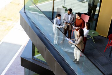 Dört profesyonel balkonda toplanıp parlak güneş ışığının tadını çıkarırken proje planlarını tartışıyorlar..