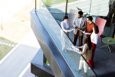 Dört profesyonel balkonda toplanıp parlak güneş ışığının tadını çıkarırken proje planlarını tartışıyorlar..