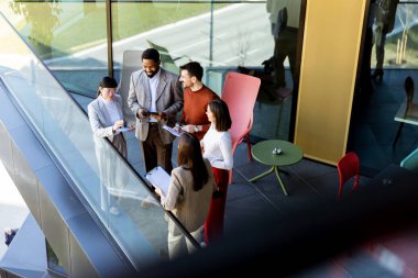 Dört profesyonel balkonda toplanıp parlak güneş ışığının tadını çıkarırken proje planlarını tartışıyorlar..