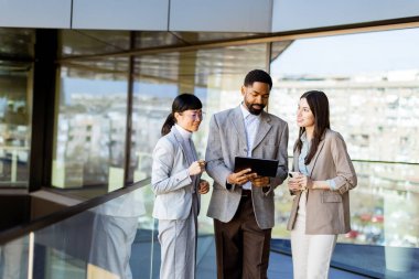 Üç meslektaş parlak bir ofiste bir tableti birlikte incelerken bir tartışmaya giriştiler. Atmosfer yaratıcılık ve işbirliği ile dolu..