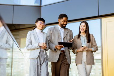 Üç meslektaş parlak, çağdaş bir ofiste yürürken, iç görü ve fikirleri paylaşırken, güneşli bir günde takım çalışmasını ve işbirliğini teşvik ederken, canlı bir tartışmanın tadını çıkarıyorlar..