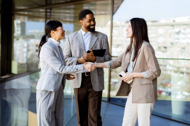 Çağdaş bir ofis ortamında sohbet eden üç profesyonel hevesle fikir alışverişinde bulundular..