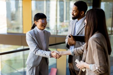 Çağdaş bir ofis ortamında sohbet eden üç profesyonel hevesle fikir alışverişinde bulundular..