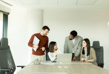 Çeşitli profesyonellerden oluşan bir grup, bir konferans masası etrafında dinamik bir beyin fırtınası yapıyor, fikirlerini paylaşıyor ve parlak bir ofis alanında dizüstü bilgisayar ve notlarla etkileşime giriyor..