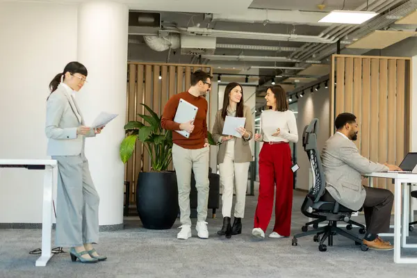 Bir grup profesyonel, dokümanları incelerken, yeşil ve çağdaş çalışma alanlarında takım çalışması ve yaratıcılığı somutlaştırırken, canlı tartışmalara girişiyor..