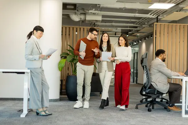 Bir grup profesyonel, dokümanları incelerken, yeşil ve çağdaş çalışma alanlarında takım çalışması ve yaratıcılığı somutlaştırırken, canlı tartışmalara girişiyor..