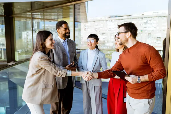 Parlak bir ofiste profesyonellerin canlı bir araya gelmesi, el sıkışmaları, gülümsemeleri ve yenilikçi stratejileri tartışmaları, ekip üyeleri arasında işbirliğini ve bağlantıyı teşvik etmeleri,.