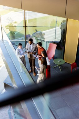 Dört profesyonel balkonda toplanıp parlak güneş ışığının tadını çıkarırken proje planlarını tartışıyorlar..