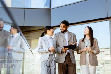 Üç meslektaş parlak, çağdaş bir ofiste yürürken, iç görü ve fikirleri paylaşırken, güneşli bir günde takım çalışmasını ve işbirliğini teşvik ederken, canlı bir tartışmanın tadını çıkarıyorlar..