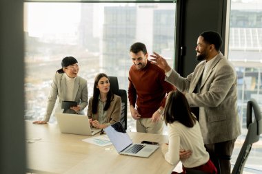Çeşitli profesyonellerden oluşan bir grup, bir konferans masası etrafında dinamik bir beyin fırtınası yapıyor, fikirlerini paylaşıyor ve parlak bir ofis alanında dizüstü bilgisayar ve notlarla etkileşime giriyor..