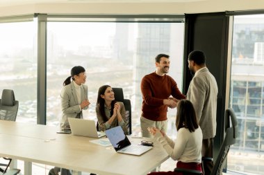 Çeşitli profesyonellerden oluşan bir grup, bir konferans masası etrafında dinamik bir beyin fırtınası yapıyor, fikirlerini paylaşıyor ve parlak bir ofis alanında dizüstü bilgisayar ve notlarla etkileşime giriyor..