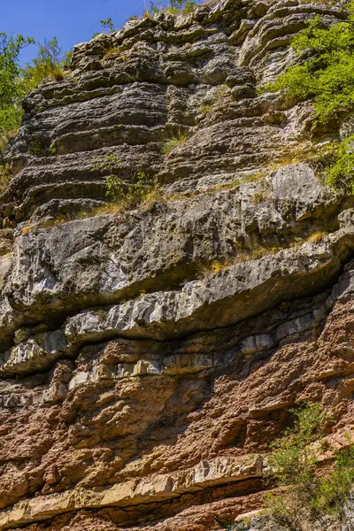 Boljetin Nehri boyunca yükselen parlak tortulu kaya katmanları, açık mavi gökyüzü ve yemyeşil bir gökyüzü altında Aşağı Kretase döneminin zengin jeolojik tarihini gözler önüne seriyor..
