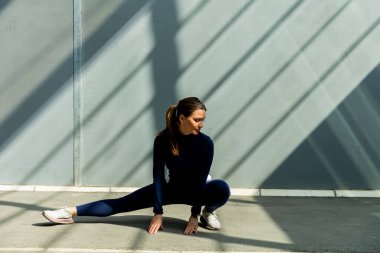 Bir kadın zarif bir şekilde yere uzanır, zarif şehir mimarisinin çarpıcı gölgeleriyle çevrili..