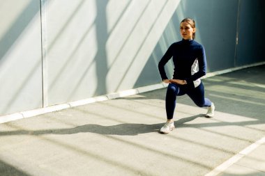 Kendini adamış bir sporcu, geometrik gölgelerin arasından süzülen yumuşak güneş ışığıyla yıkanmış açık bir yüzeyde hamleler yapar..