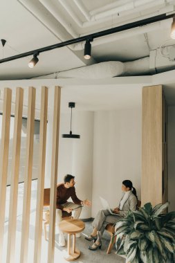 İki profesyonel şık bir ofis ortamında düşünceli bir tartışmaya giriştiler. Çağdaş koltuklarda rahatça otururken fikir alışverişinde bulundular..