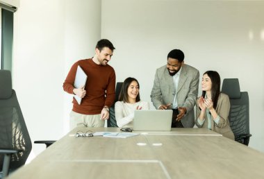 Çeşitli profesyonellerden oluşan bir grup, bir konferans masası etrafında dinamik bir beyin fırtınası yapıyor, fikirlerini paylaşıyor ve parlak bir ofis alanında dizüstü bilgisayar ve notlarla etkileşime giriyor..