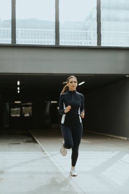 Kararlı bir koşucu, modern bir tünelde yürürken temposunu korur. Yumuşak, ortam aydınlatmasıyla aydınlanır..