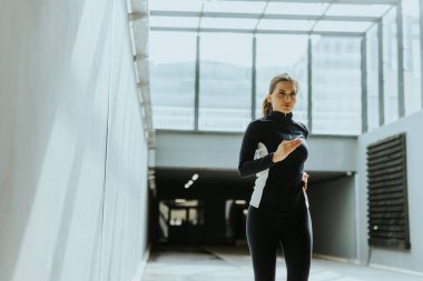 Şık bir şehir koridorunda çalışan kararlı bir koşucu, güneş ışığının büyük cam panellerden geçerek atletizmine odaklanmasını sağlıyor..