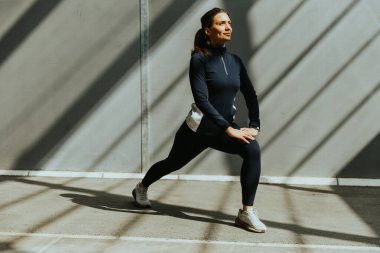 Bir kadın hamlesini yapıyor, güneş ışınlarıyla aydınlatılıyor, sağlıklı bir yaşam tarzını kucaklıyor..