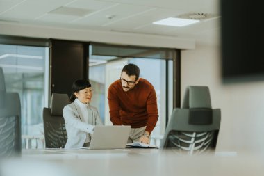 İki profesyonel, şık bir ofis çalışma alanında dizüstü bilgisayardaki bilgileri incelerken canlı bir tartışmaya girişiyor. Coşkuları takım çalışması ve yenilikleri vurguluyor.