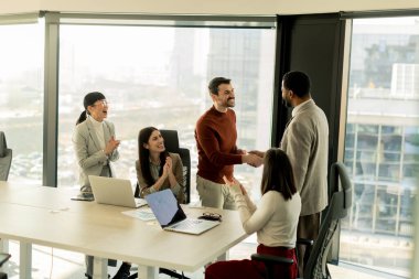 Çeşitli profesyonellerden oluşan bir grup, bir konferans masası etrafında dinamik bir beyin fırtınası yapıyor, fikirlerini paylaşıyor ve parlak bir ofis alanında dizüstü bilgisayar ve notlarla etkileşime giriyor..