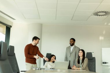 Parlak bir ofiste, çeşitli profesyonellerden oluşan bir grup dizüstü bilgisayarın etrafında toplanarak, dinamik tartışmalar, takım çalışması ve yaratıcılıkla uğraşırken içgörü ve stratejilerini paylaşıyor..