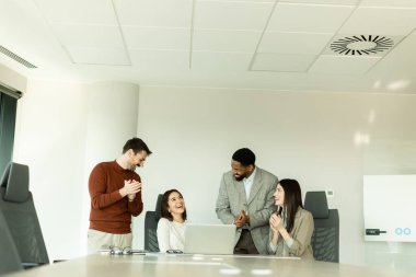 Parlak bir ofiste, çeşitli profesyonellerden oluşan bir grup dizüstü bilgisayarın etrafında toplanarak, dinamik tartışmalar, takım çalışması ve yaratıcılıkla uğraşırken içgörü ve stratejilerini paylaşıyor..