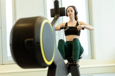 Gelişmiş bir makinede özenle sıralanmış, odaklanmış ve kararlı, şık bir spor salonunda fitness rutinine dalmış bir adam..