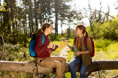 İki arkadaş kahkahalarını ve hikayelerini paylaşırken güneşli bir yolda taze bir kahve molası veriyorlar..
