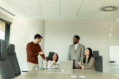 Parlak bir ofiste, çeşitli profesyonellerden oluşan bir grup dizüstü bilgisayarın etrafında toplanarak, dinamik tartışmalar, takım çalışması ve yaratıcılıkla uğraşırken içgörü ve stratejilerini paylaşıyor..