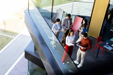 Dört profesyonel balkonda toplanıp parlak güneş ışığının tadını çıkarırken proje planlarını tartışıyorlar..