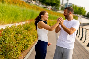 Neşeli çift neşeli bir anı paylaşıyor, neşeli bir şehir yolunda koşarken gülen ve şakacı bir şekilde el ele tutuşan