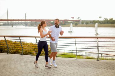 Odaklanmış bir adam öğleden sonra saatlerinde nehir kenarında egzersiz yaparken sudan zevk almak için duraksar.