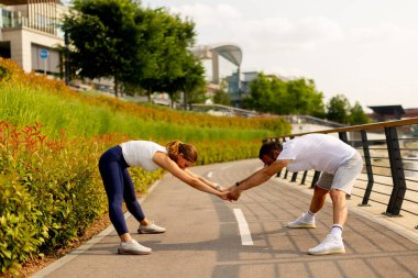 Odaklanmış bir adam öğleden sonra saatlerinde nehir kenarında egzersiz yaparken sudan zevk almak için duraksar.