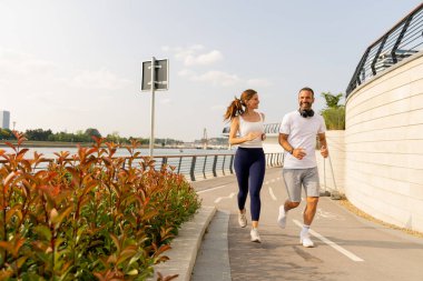 Odaklanmış bir adam öğleden sonra saatlerinde nehir kenarında egzersiz yaparken sudan zevk almak için duraksar.