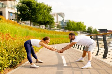 Odaklanmış bir adam öğleden sonra saatlerinde nehir kenarında egzersiz yaparken sudan zevk almak için duraksar.