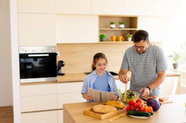 Bir baba ve kızı yemek hazırlarken, yemek tarifi kitabını okurken ve ev yapımı yemekleri davetkâr mutfağında yerken kaliteli zaman geçirmekten zevk alır..