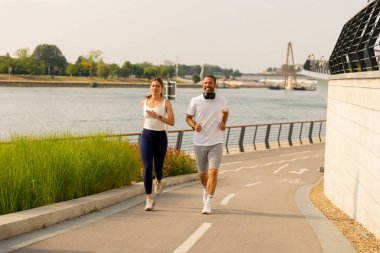 Genç bir çift kumsalda eğlenerek vakit geçirir. Kadın, erkeğin sırtında neşe içinde ata biner.