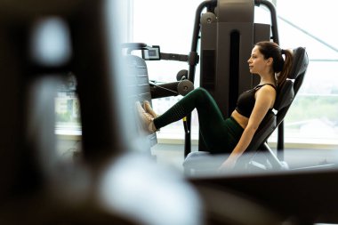 Çağdaş bir spor salonunun içinde bacağa baskı yapan kararlı bireyler daha düşük vücut gücü ve fitness seviyelerini arttırır..