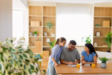 Üç aile üyesi, bitkilerle çevrili rahat bir masada neşeli bir aktiviteye girişiyor. Yaratıcılık ve bağlantı dolu anları paylaşıyorlar..