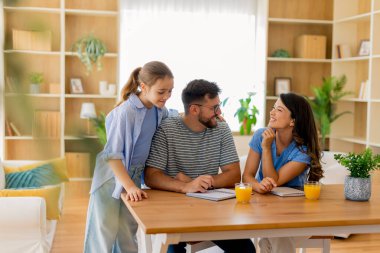 Neşeli bir aile, sıcak evlerinde içkilerini yudumlarken beyin fırtınası yaparak verimli bir öğleden sonranın tadını çıkarır..