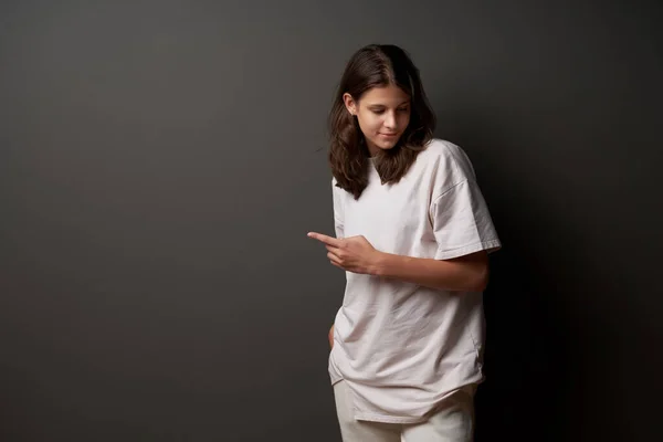Casual Relaxed Teen Girl Pointing Finger Side Dark Grey Wall — Zdjęcie stockowe