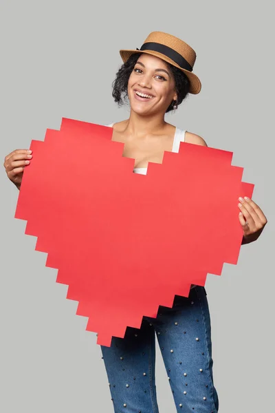 Mixed race african american caucasian girl in straw hat holding big paper pixel style heart shape with copy space for text