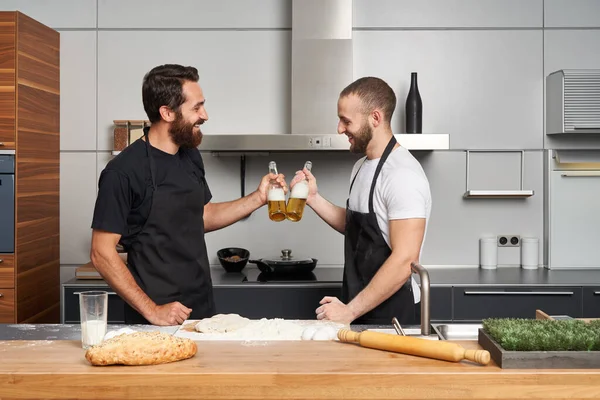 两个朋友在现代厨房里做面包或披萨和喝啤酒都很开心 — 图库照片