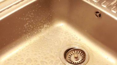  Kadın mutfak lavabosunu ve musluğu yıkıyor. Ev işleri ve ev idaresi kavramı.