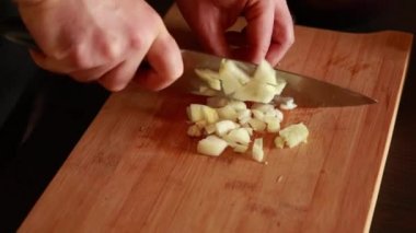 man hands cutting white onion close up in wooden board